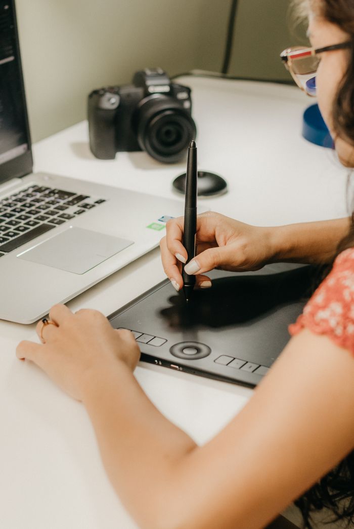Home Young woman working with graphic tablet and laptop in a creative workspace.